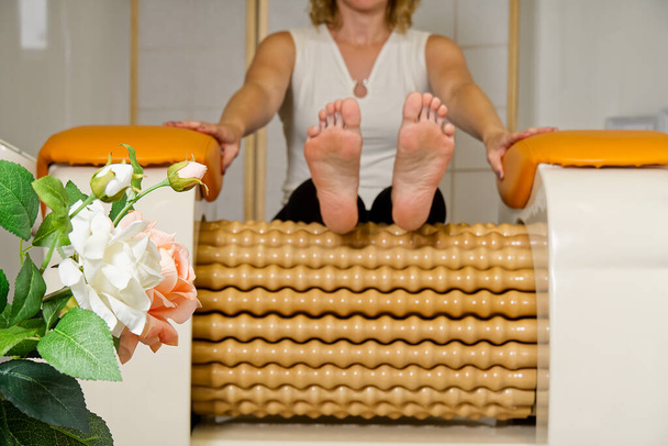 Frau, die Massage für Bein Oberschenkelknochen. Roll Massage-Maschine ist eine Möglichkeit, die Figur zu formen. Hautpflege, Körperpflegekonzept. moderne Entspannungsmassagegeräte. - Foto, Bild