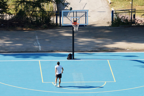 Varna, Bulgária - 22 de agosto de 2020: jovem treinando com uma bola em um campo de basquete ao ar livre - Foto, Imagem