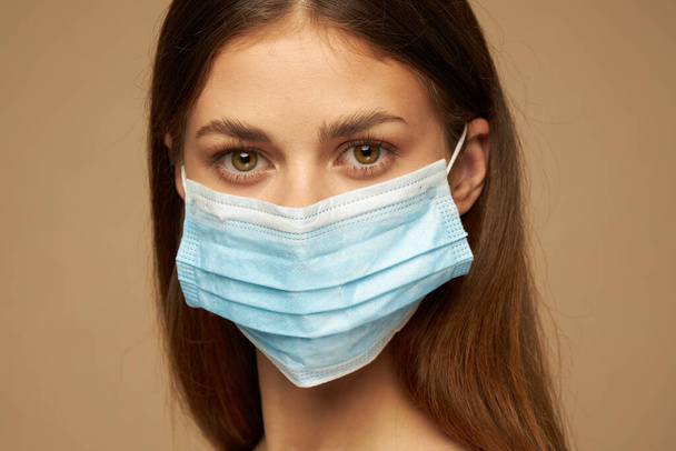 Brunette woman in a medical mask looks forward - Valokuva, kuva