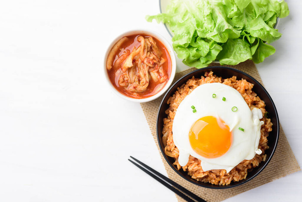 Beyaz masadaki bir kasede kızarmış yumurtalı kimchi pilavı, Kore yemeği, Top View. - Fotoğraf, Görsel
