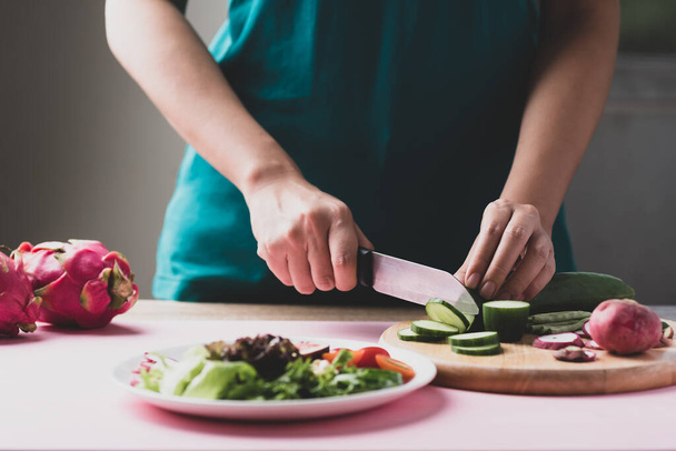 Γυναίκα κοπή αγγούρι προετοιμασία για vegan σαλάτα, Υγιεινά τρόφιμα - Φωτογραφία, εικόνα