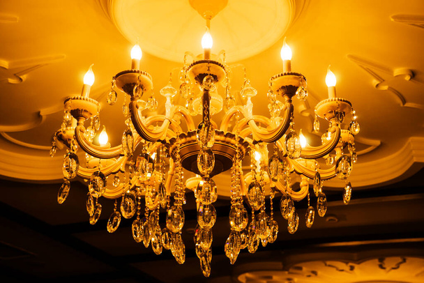 Потолочная люстра классической винтажной формы из хрусталя и стекла с лампами в форме свечи. - Фото, изображение