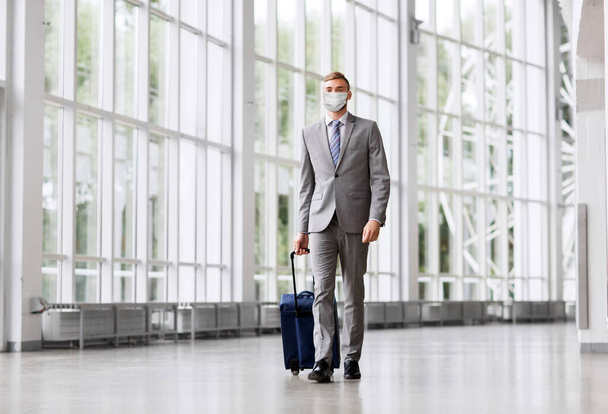 businessman in mask with travel bag at airport - Foto, Bild