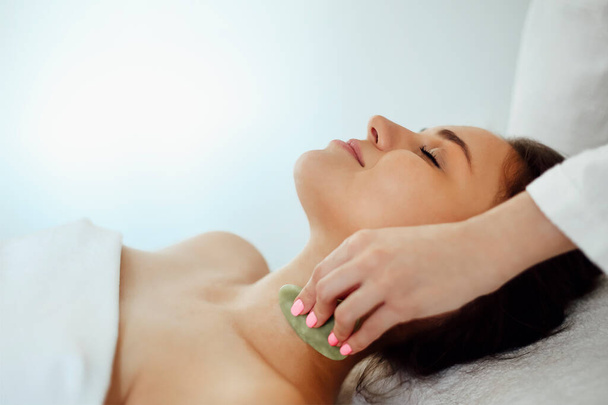 Massage du visage gua sha ou soins de beauté dans le salon de spa Massage du visage ou soins de beauté dans le salon de spa - Photo, image