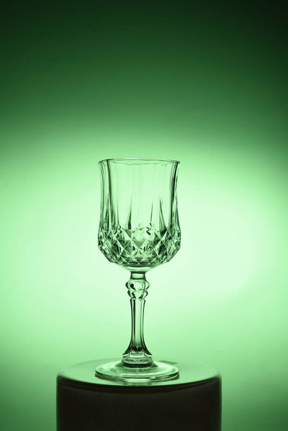 Wineglass on the light background. Fine cristal glassware concept. Vertical, toned in green - Photo, image