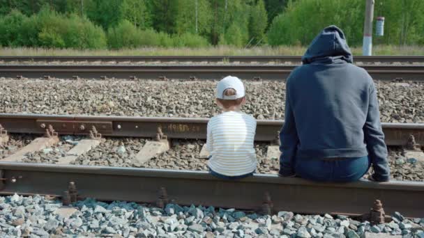 Видео девочки и мальчика, сидящих на рельсах - Кадры, видео