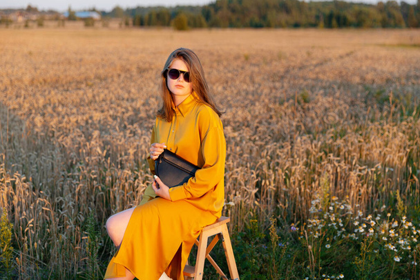 Una giovane donna posa in un abito di seta giallo alla moda.  - Foto, immagini