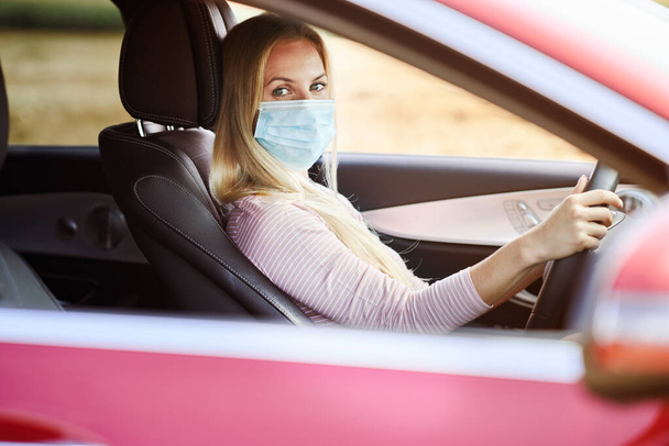  Femme conduisant une voiture portant un masque de protection                               - Photo, image