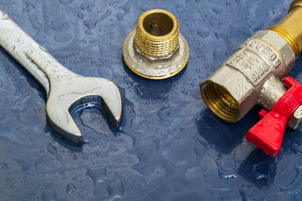 Grifo de fontanería y llave inglesa en gotas de agua durante la reparación del equipo durante un accidente - Foto, Imagen