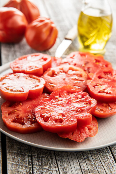 Sliced red beefsteak tomatoes on plate. - Фото, изображение