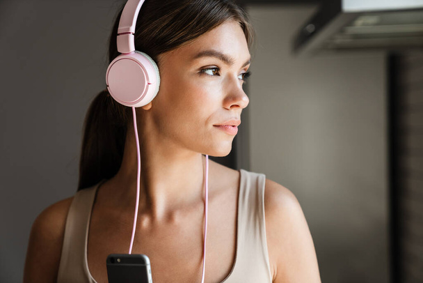 Beautiful young woman with headphones listening to music at home - Фото, изображение