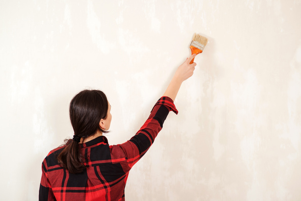 Woman painting interior wall in new house. Home decoration concept. Apartment repair. Female painting wall with paint brush. - Foto, Bild