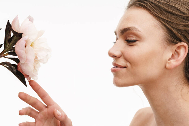 Portrait of a beautiful smiling young topless woman smelling flowers isolated over white background - Photo, image