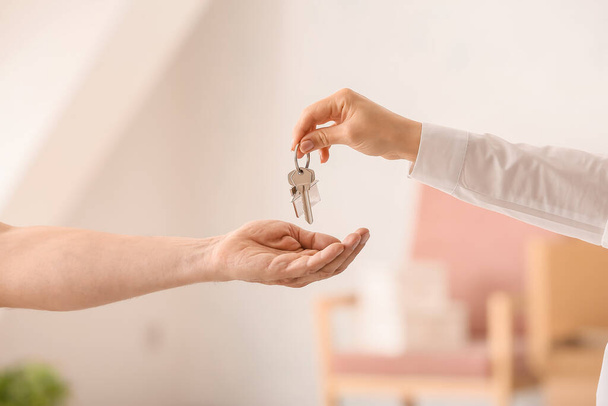 Real estate agent giving keys from house to new owner indoors - Foto, afbeelding