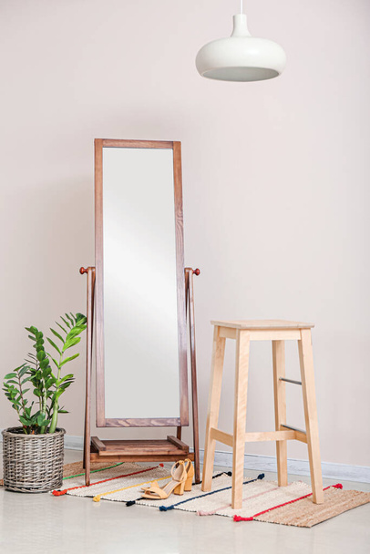 Espelho grande com tamborete e planta de sala perto da parede clara no quarto - Foto, Imagem