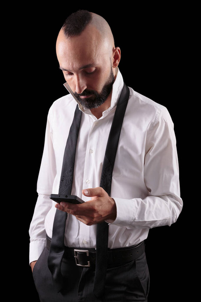 Jóképű spanyol férfi átnézi a telefonját öltözködés közben. - Fotó, kép