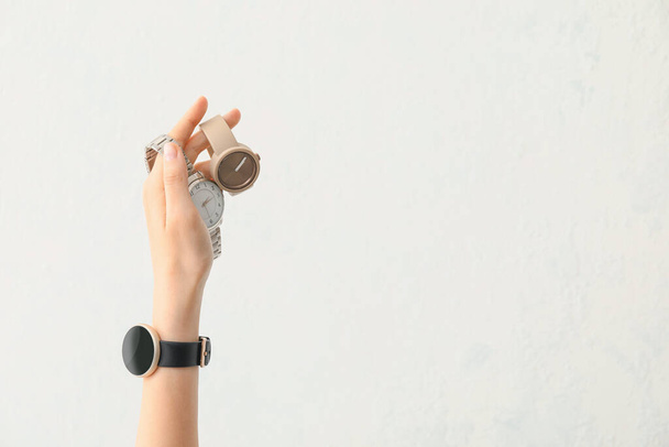 Жіноча рука зі стильними наручними годинниками на білому тлі
 - Фото, зображення