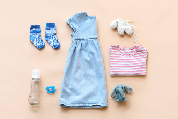 Baby clothes with bottle, pacifier and toys on color background - Photo, Image