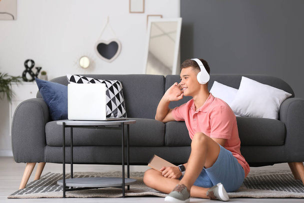 Εφηβικό αγόρι με φορητό υπολογιστή ακούγοντας μουσική στο σπίτι - Φωτογραφία, εικόνα