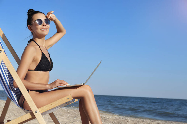 Beautiful young woman with laptop on sea beach - Photo, Image