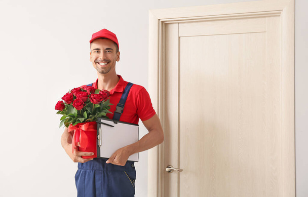 Livraison homme avec bouquet de fleurs près de la porte du client - Photo, image