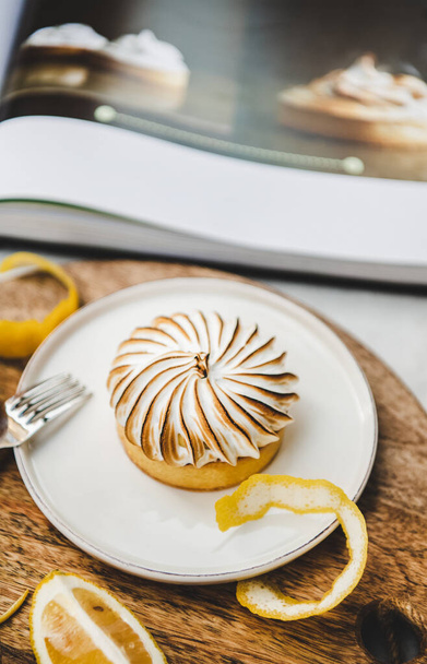 Lemon tart with merengue sweet dessert on plate over white marble table in cafe, close-up, selective focus. French cuisine, comfort food, fine dining concept - Foto, imagen