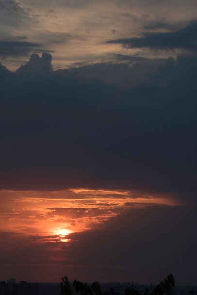 Een onafgewerkt beeld van een voorbijgaande dag bij zonsondergang boven een grote stad in een krachtig contrast van het ontmoeten van de nacht en een lange hete dag - Foto, afbeelding