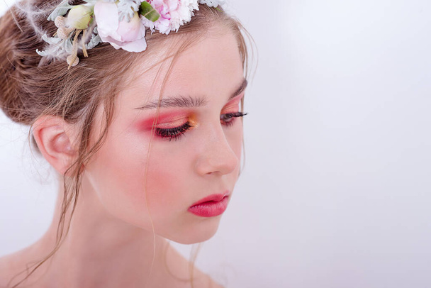Extra close up portrait of a beauty young girl with nude fashion bright make-up, a hairstyle on head, a hoop made of fresh flowers: peons, field flowers, eucalyptus, ranunculus. Clean skin. Bridesmaid - Фото, изображение