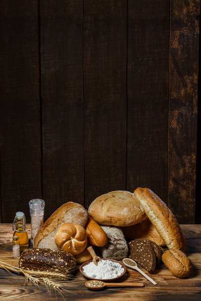 Different loaves of bread cooked with flour and gluten-free wheat on a wooden table - Foto, Imagem