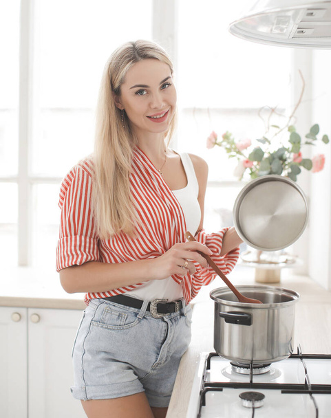 Beatiful smiling woman is cooking in kichen at home - Foto, Bild