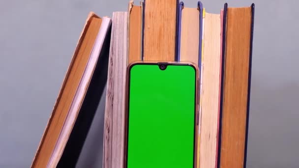 İnternet kütüphanesi. Bir yığın kitap ve yeşil ekranlı akıllı telefon. Eğitim konsepti. Klasik edebiyat okuyorum. Bilimsel araştırma. Uzayı kopyala E-öğrenme  - Video, Çekim