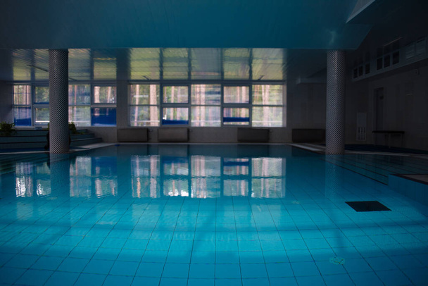 pool room is reflected in blue water, daylight in windows, glare from light on water - Foto, Imagen
