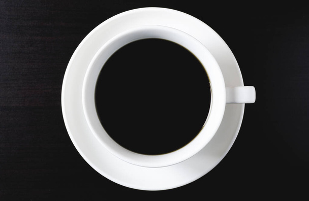 Top kilátás fekete kávé fehér csésze sötét fa padló - Fotó, kép