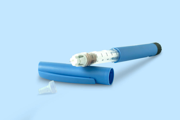 青色の背景にインスリンペン糖尿病治療のための注射に医療機器が使用されています.健康管理とセルフケアの概念 - 写真・画像