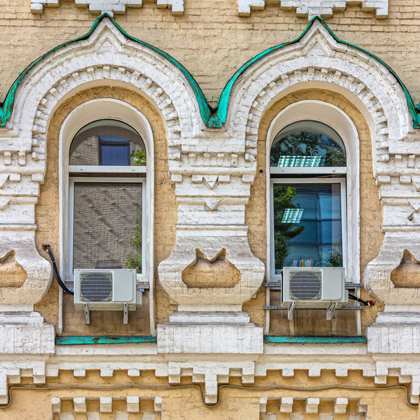 Moskova, Venäjä, 08.21.2020. 1800-luvulla rakennetun talon muuri leskille ja orvoille, ikkunoille ja arkistoille on sisustettu pseudovenäläiseen tyyliin. Muoviset ikkunat ja ilmastointilaitteet - Valokuva, kuva