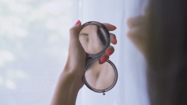 Cerrar plano de reflexión de la mujer en un espejo de bolsillo, la aplicación de maquillaje en polvo con el uso de un cepillo  - Metraje, vídeo