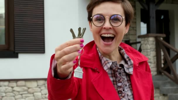 Bella donna con gli occhiali detiene le chiavi della nuova casa. Business lady è felice di acquistare un appartamento. - Filmati, video