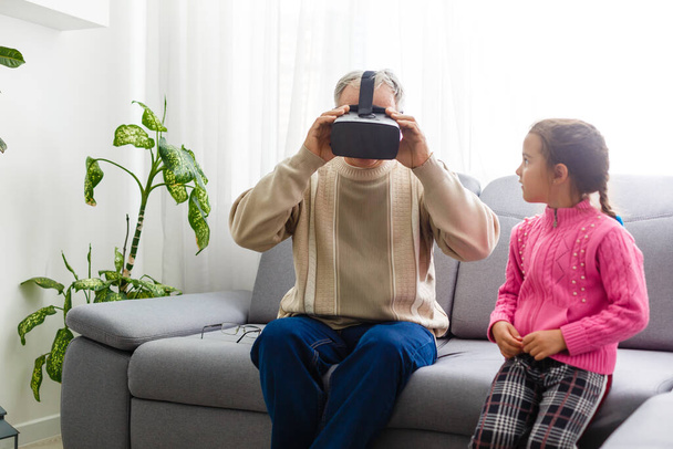 Senior man draagt virtual reality bril thuis - Foto, afbeelding