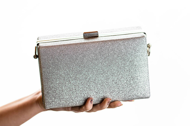 Vrouw hand houden glittervormige zilveren clutch tas geïsoleerd op witte achtergrond met kopieerruimte. - Foto, afbeelding