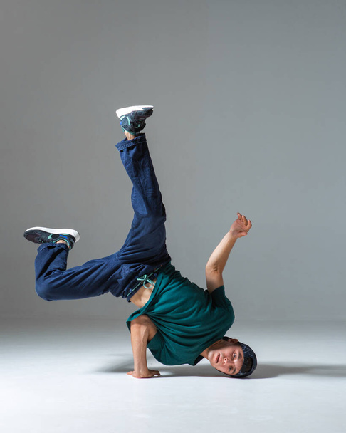 Cool guy breakdancer dancing on one hand isolated on gray background. Breakdance poster - Photo, Image