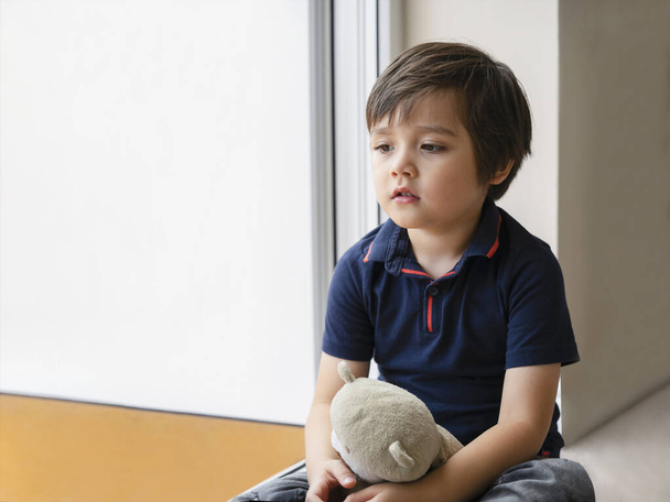 Emotional portrait sad kid sitting with teddy bear, Lonely kid sitting on floor in corner and looking down,Little boy wall corner punishment sitting,Family violence concept. - Photo, Image