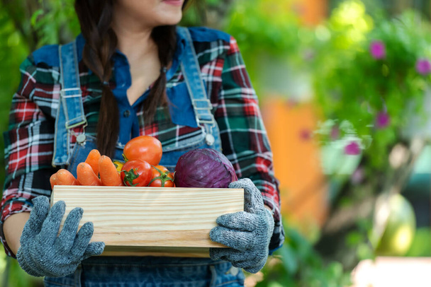 Hand in Hand. Asiatische glückliche Bäuerin mit einem Korb Bio-Gemüse im Weinberg auf dem Land zum Verkauf auf den Märkten - Foto, Bild