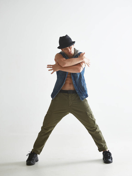 Cool young guy breakdancer in hat dancing hip-hop in studio isolated on white background. Break dance lessons - Foto, Bild