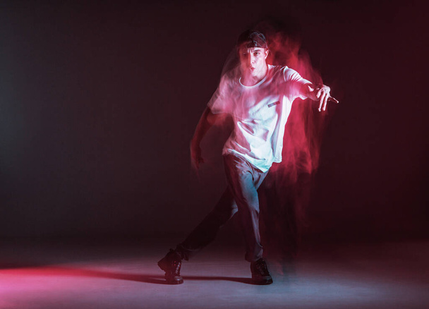 Stylish young guy breakdancer dancing hip-hop in neon light. Dance school poster. Long exposure shot - Foto, Imagen