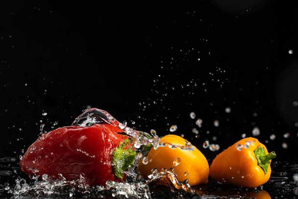 Sweet peppers on a black background with drops and splashes of water - Foto, immagini