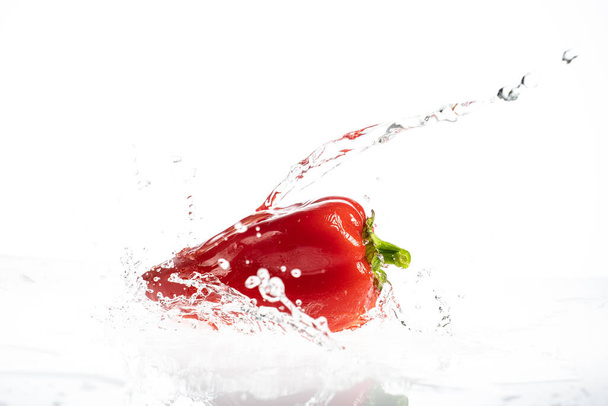 Sweet peppers on a white background with drops and splashes of water - Фото, зображення