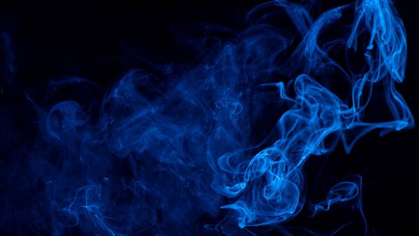 Conceptual image of blue color smoke isolated on dark black background, Halloween design element concept. - Photo, Image
