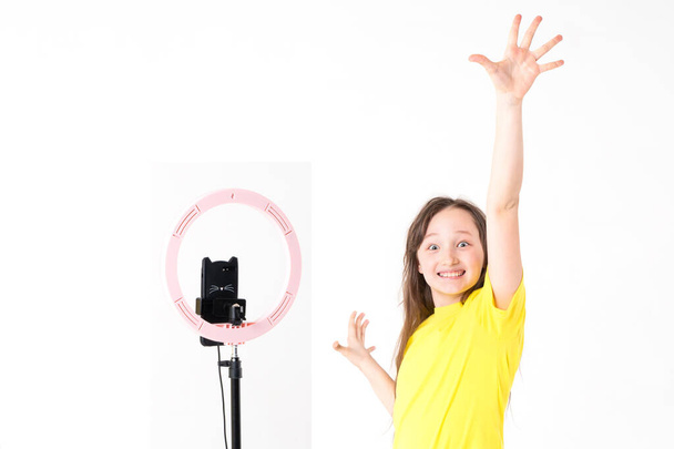 Un'adolescente guarda la telecamera e alza la mano con un'espressione di gioia sul viso. - Foto, immagini
