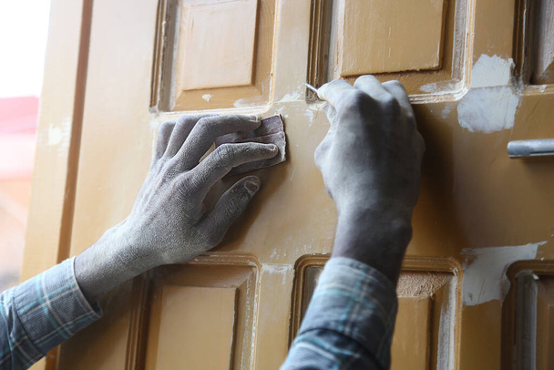 Sluiten van timmerlieden handen met behulp van spijker en schuurpapier prachtig gesneden houten deur / plank op het werk, indiaanse stijl ambacht, timmerwerk. - Foto, afbeelding