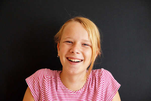.portrait of a laughing teenage girl on a black background - Photo, Image